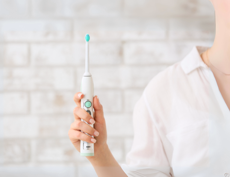 Person holding a modern electric toothbrush against a light bathroom background